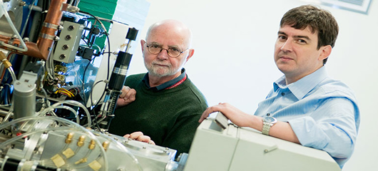 Tom Ruth and Dr. Francois Benard stand next to a cyclotron at the BC Cancer Agency in Vancouver. Photo: Martin Dee