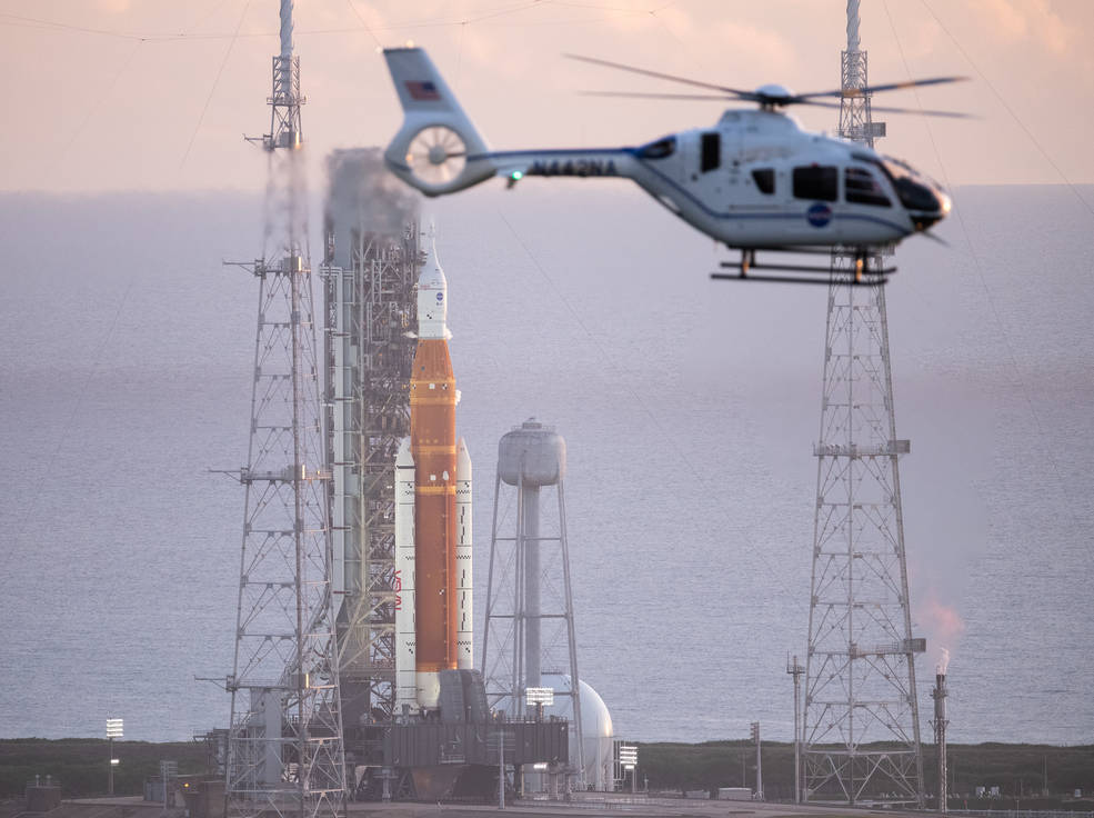 A NASA helicopter flies past the agency’s Space Launch System