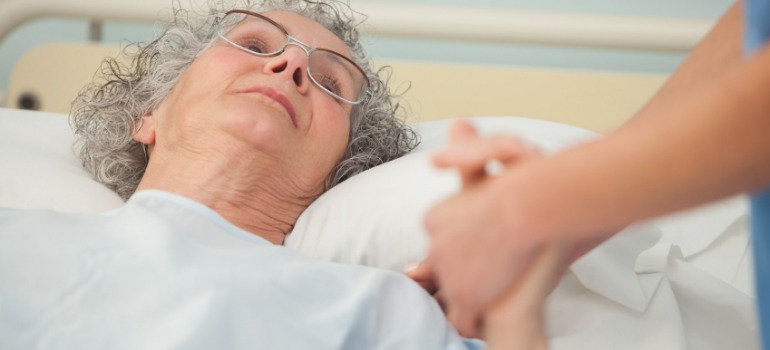 Nurse caring about old woman lying in bed