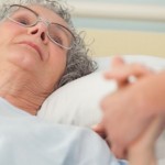 Nurse caring about old woman lying in bed