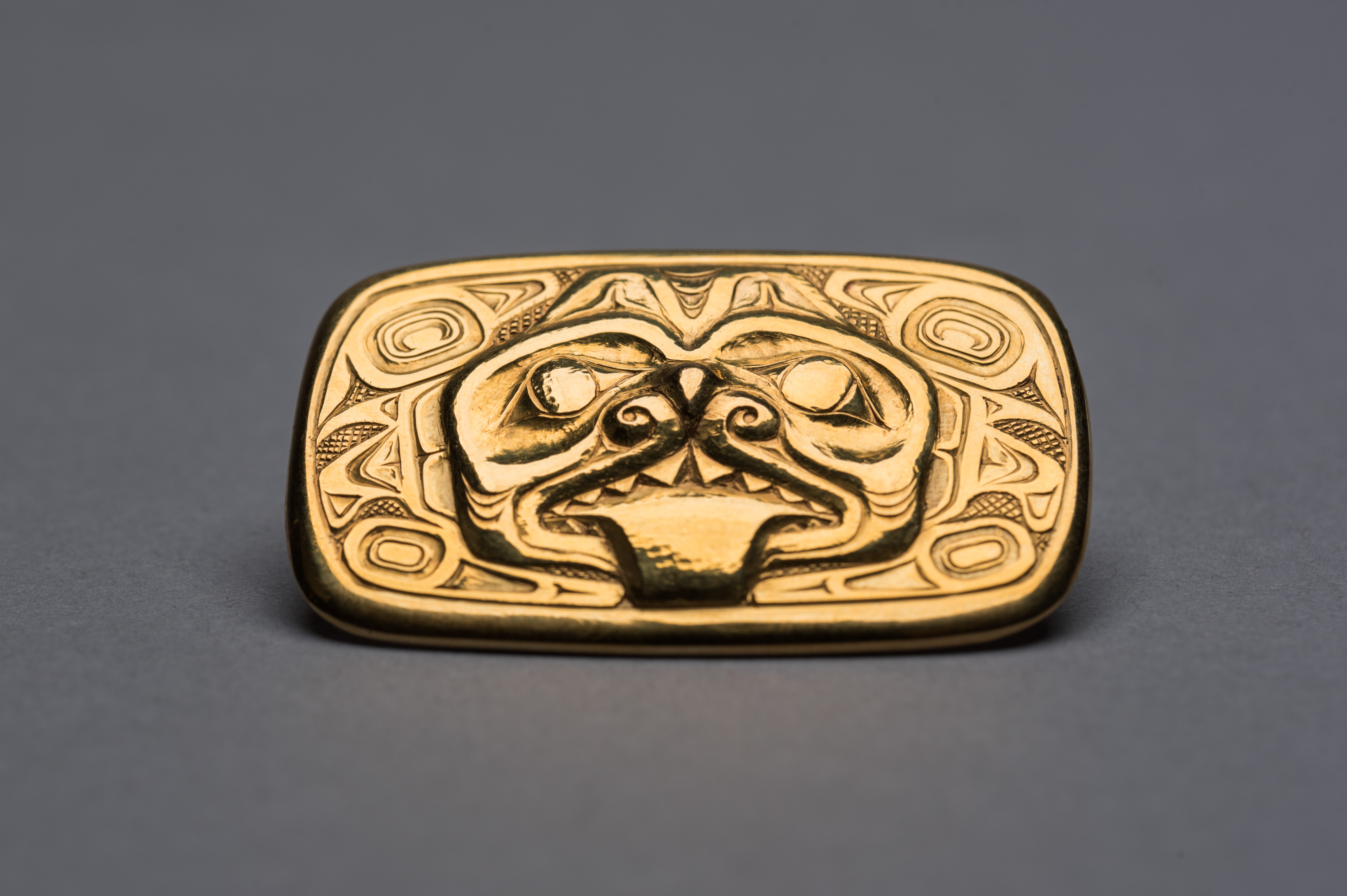 A gold brooch with a dogfish motif, circa 1963, created by renowned Haida artist Bill Reid is part of a collection donated to the Museum of Anthropology by late Calgary philanthropist Margaret (Marmie) Perkins Hess. Credit: Martin Dee/University of British Columbia