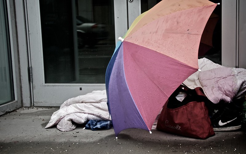 Homeless person sheltered by a large umbrella in a doorway