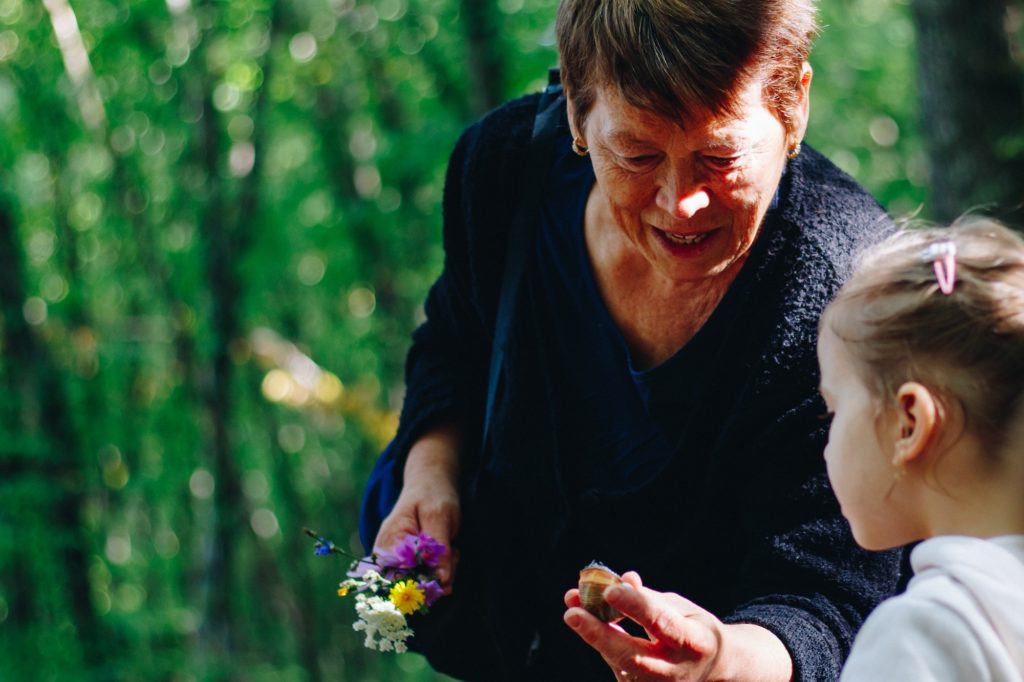 an older lady holding a snail shell and showing it to a young girl
