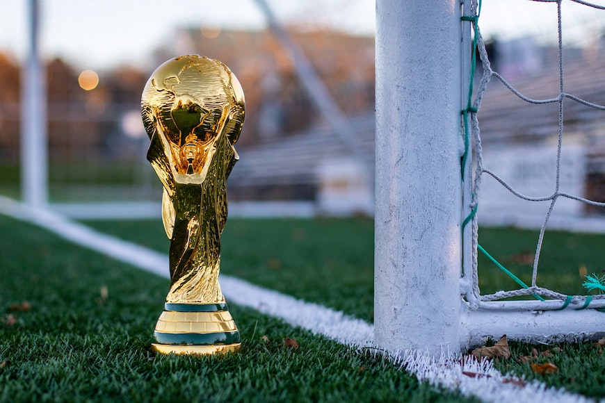 FIFA World Cup trophy sitting on the goal line of a soccer goal