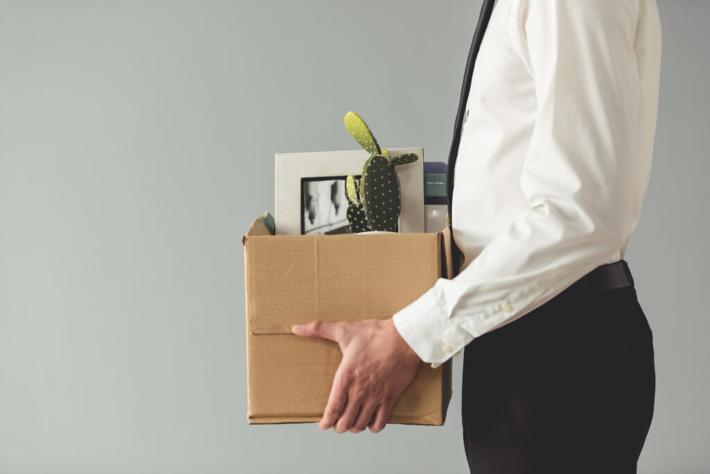 Getting fired. Cropped image of businessman in formal wear holding a box with his stuff, on gray background