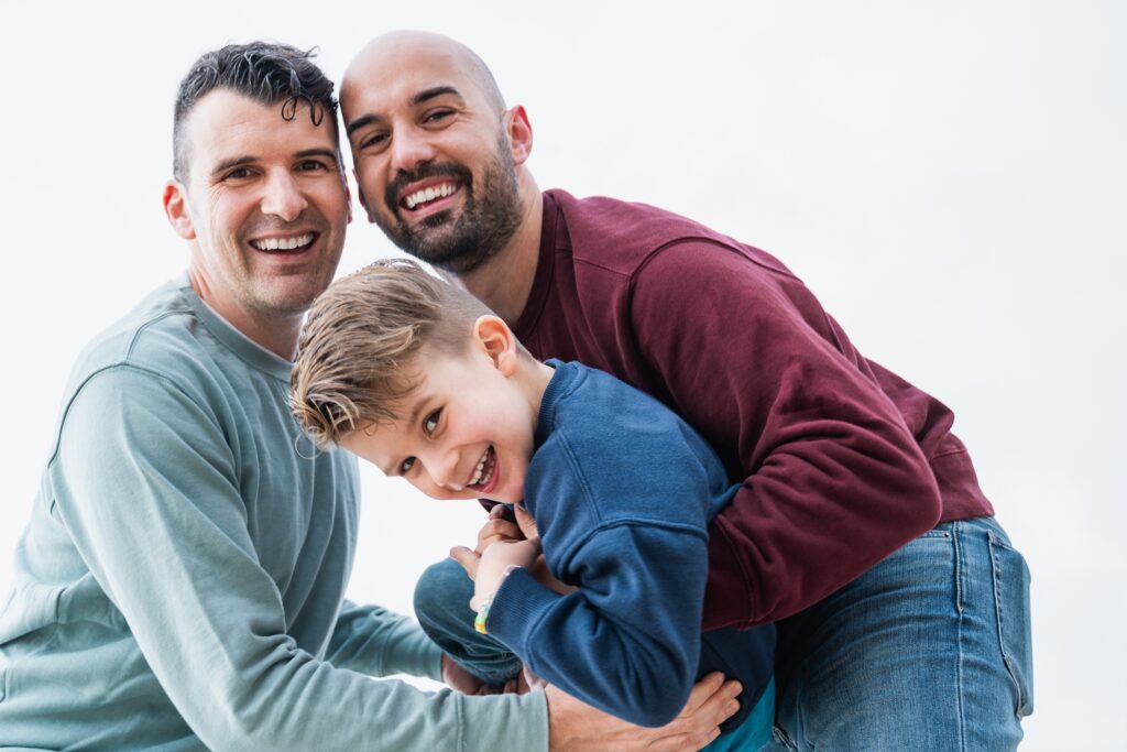 A male same-sex couple embracing a male child.
