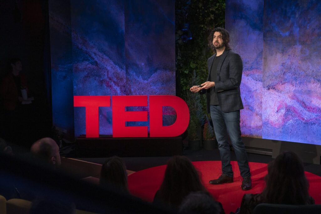 Dr. Azim Shariff on a stage giving a talk at a TED Conference