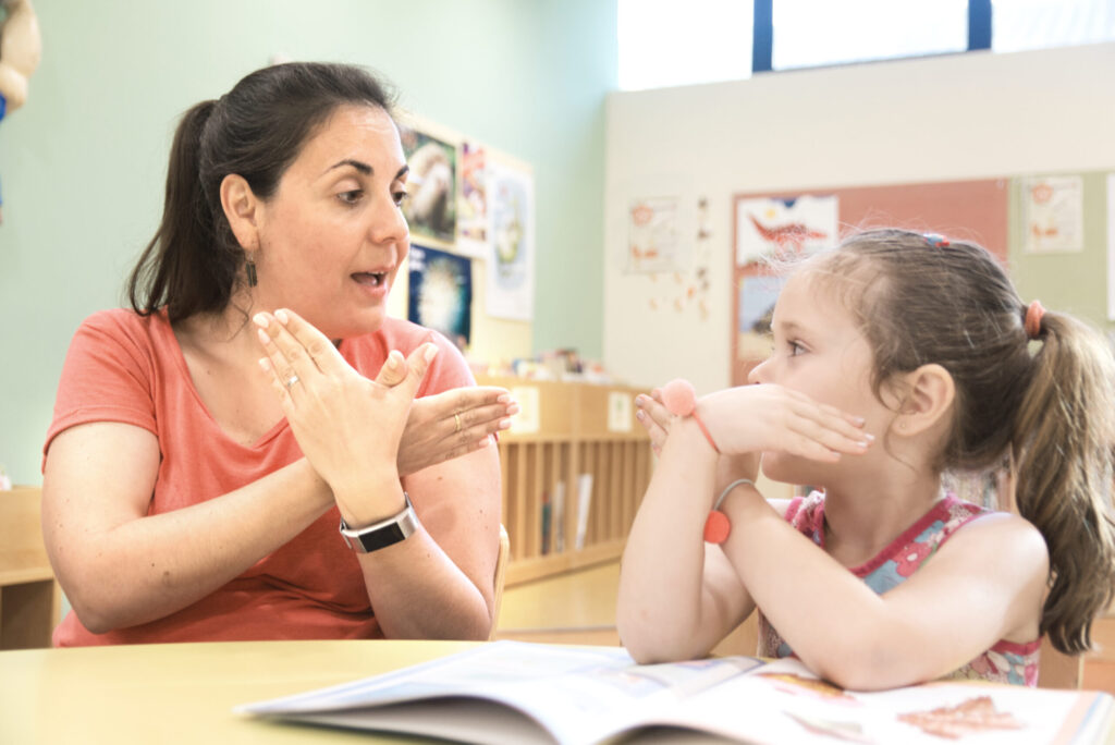 Sign language teacher in an extra tutoring class with a deaf child girl using American Sign Language.