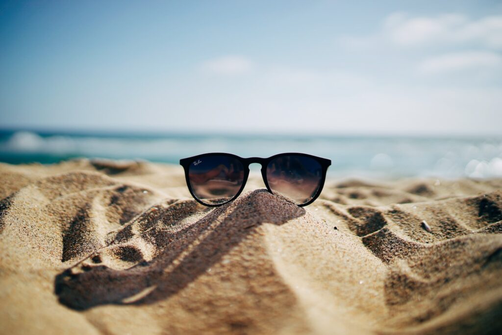 a pair of sunglasses on a sandy beach