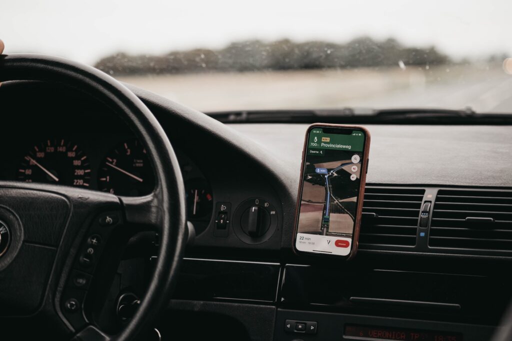 Smartphone turned-on with a navigation app on the screen in vehicle mount inside vehicle