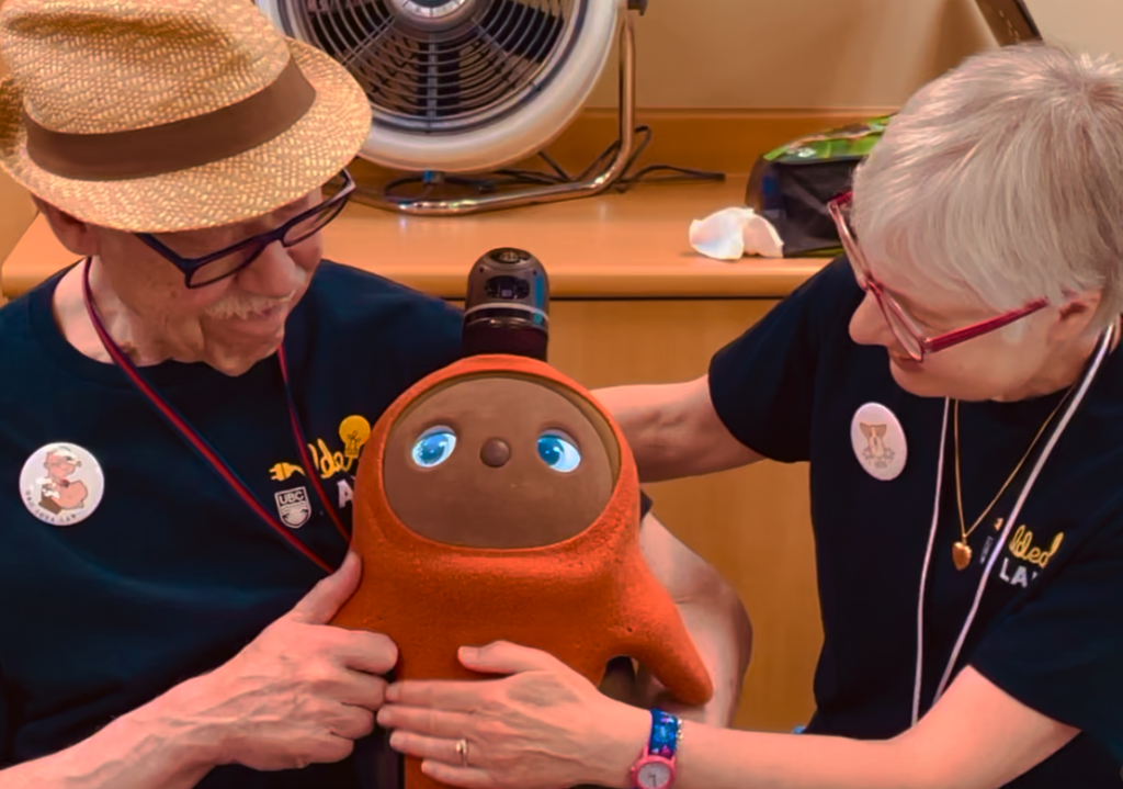 Two seniors interacting with a robot named Mango.
