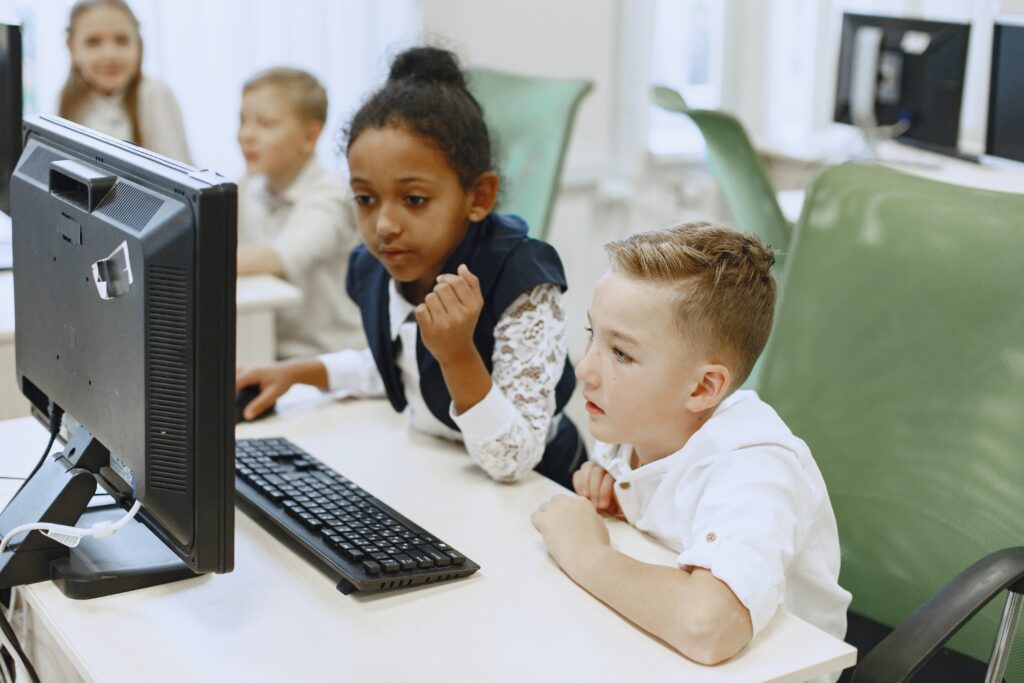 Two kids looking at a desktop computer.