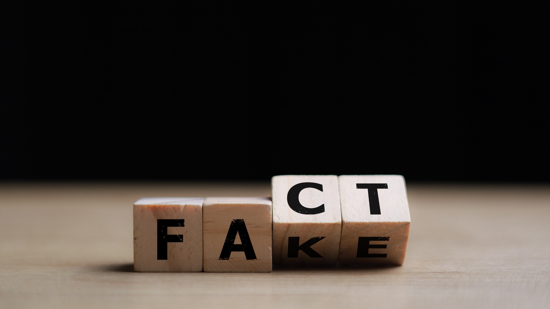 Wooden blocks spell 'FAKE' and 'FACT,' highlighting the blurred line between truth and misinformation—relating to a global study on susceptibility to fake news
